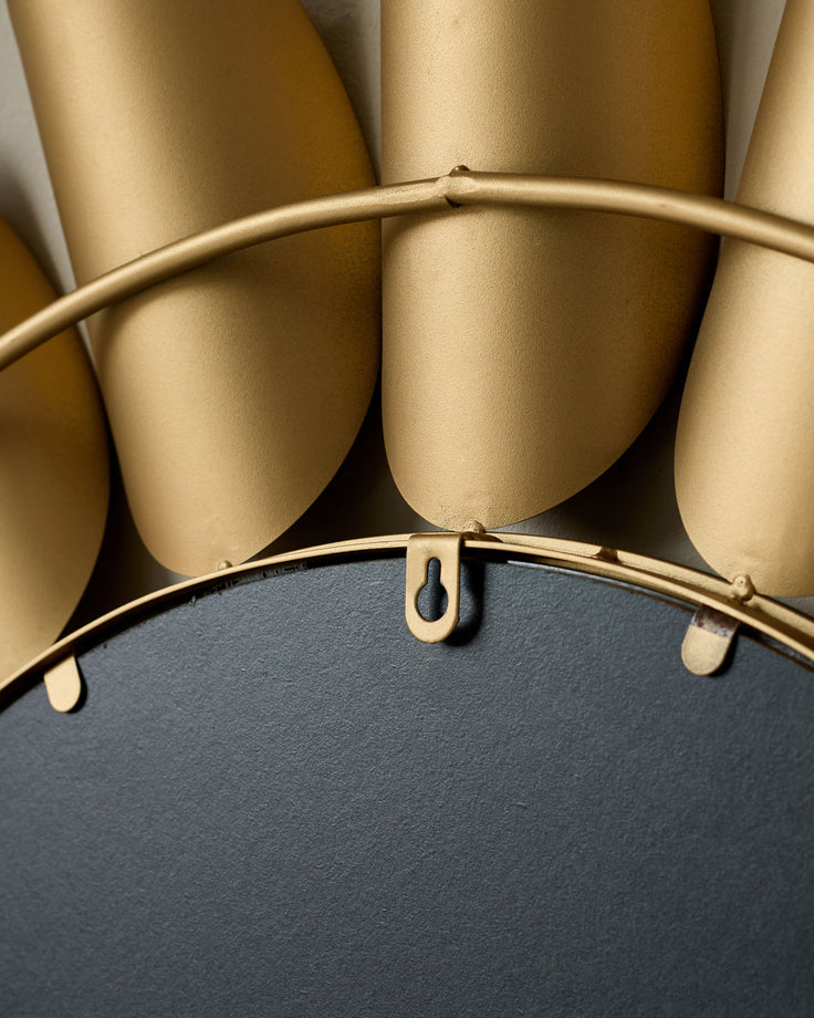 Gold round wall mirror with curved frame detail and mounting hardware visible against neutral background.