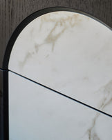 Archie bedside table with natural marble top and black metal frame, curved arch detail visible from above.