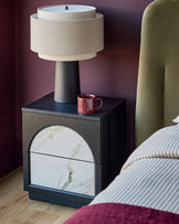 Archie bedside table with dark wood frame, white marble drawer front, and ceramic top, styled in a bedroom setting.