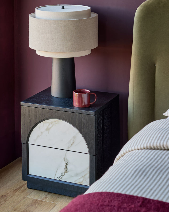 Archie bedside table with dark wood frame, white marble drawer front, and ceramic top, styled in a bedroom setting.