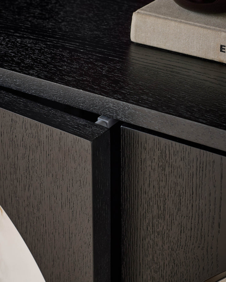 Black wood sideboard with textured dark grain finish and minimalist handle detail, shown at angle.