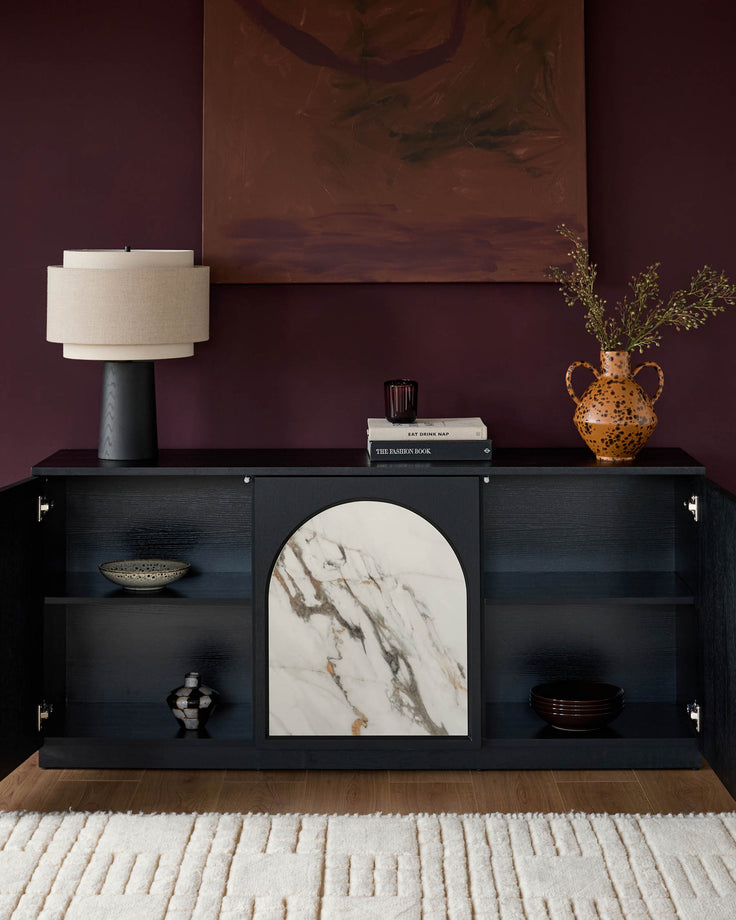 Large black sideboard with marble insert, open shelving, and closed cabinet doors with handles displayed in styled room setting.