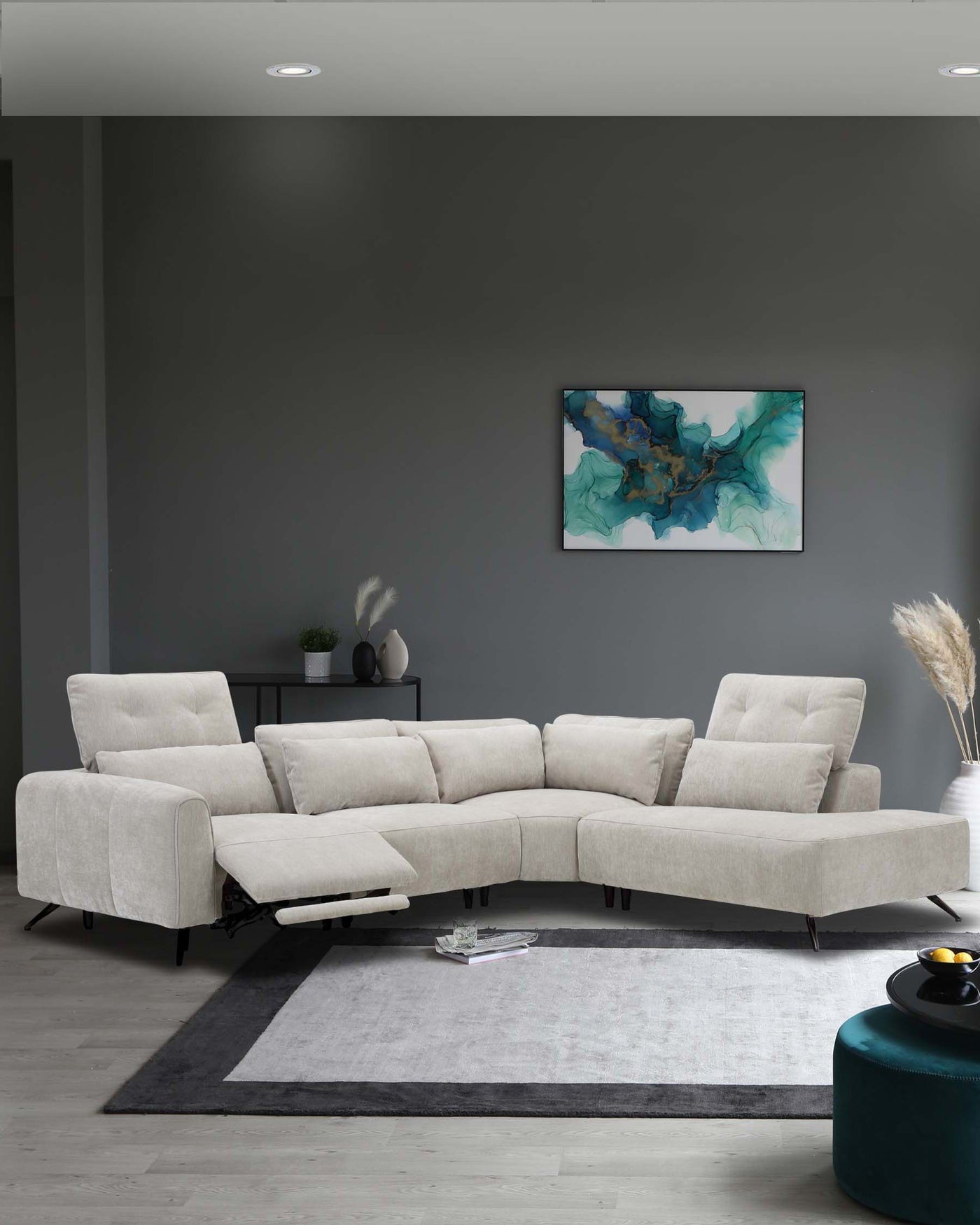 Modern light beige upholstered sectional sofa with adjustable headrests and a chaise lounge end, set on a large off-white and dark grey area rug, accompanied by a circular dark green ottoman and a sleek black side table holding decorative items.