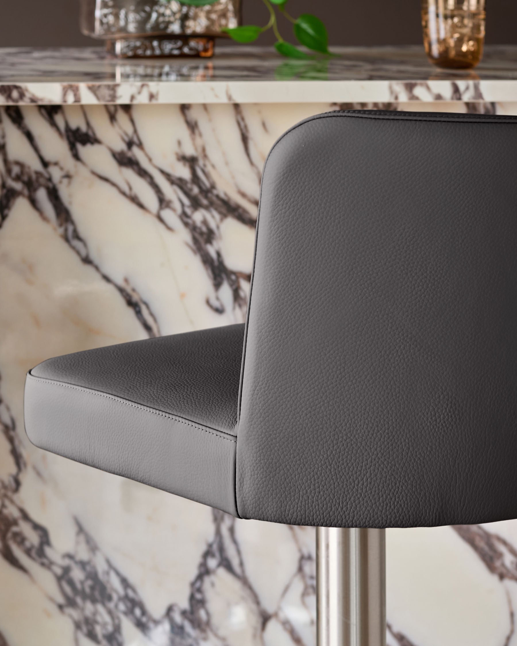 Dark grey real leather gas lift bar stool with curved backrest, shown from side angle against marble-patterned table.