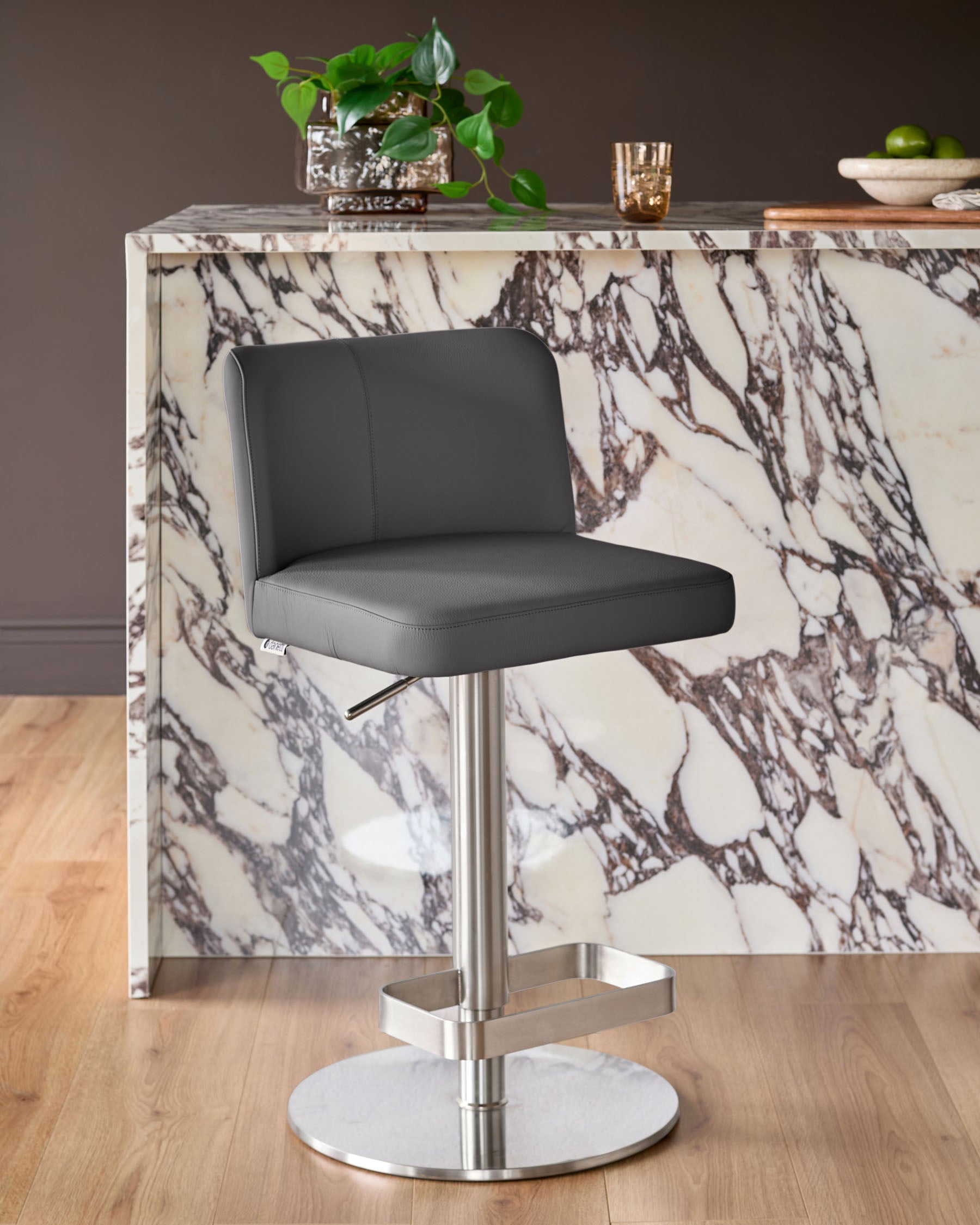 Dark grey leather gas lift bar stool with brushed steel base, positioned at marble-effect kitchen counter.