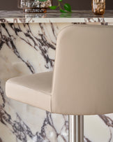 Arlo light grey leather gas lift bar stool, side view showing curved backrest and seat with metal base against marble table.