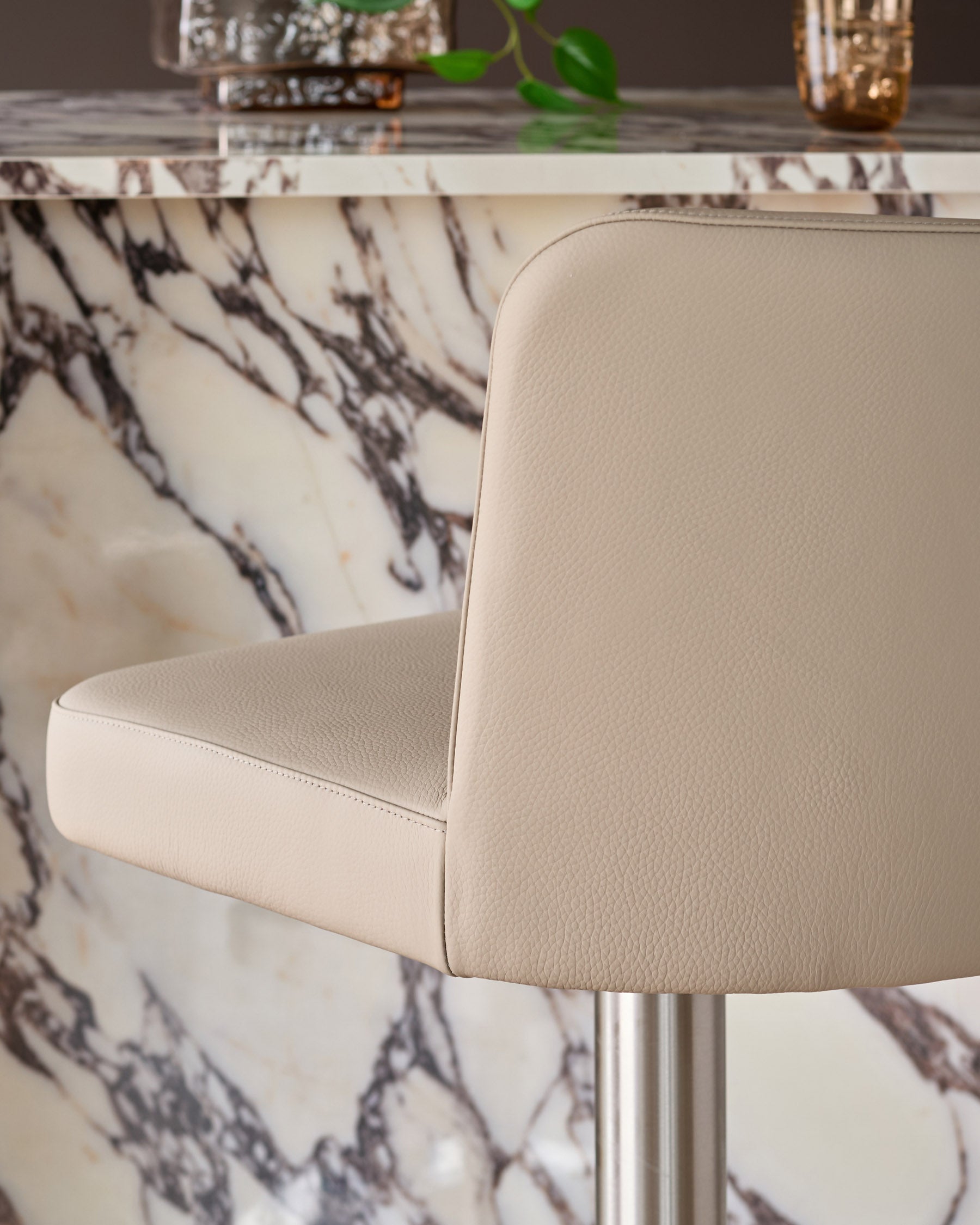 Arlo light grey leather gas lift bar stool, side view showing curved backrest and seat with metal base against marble table.