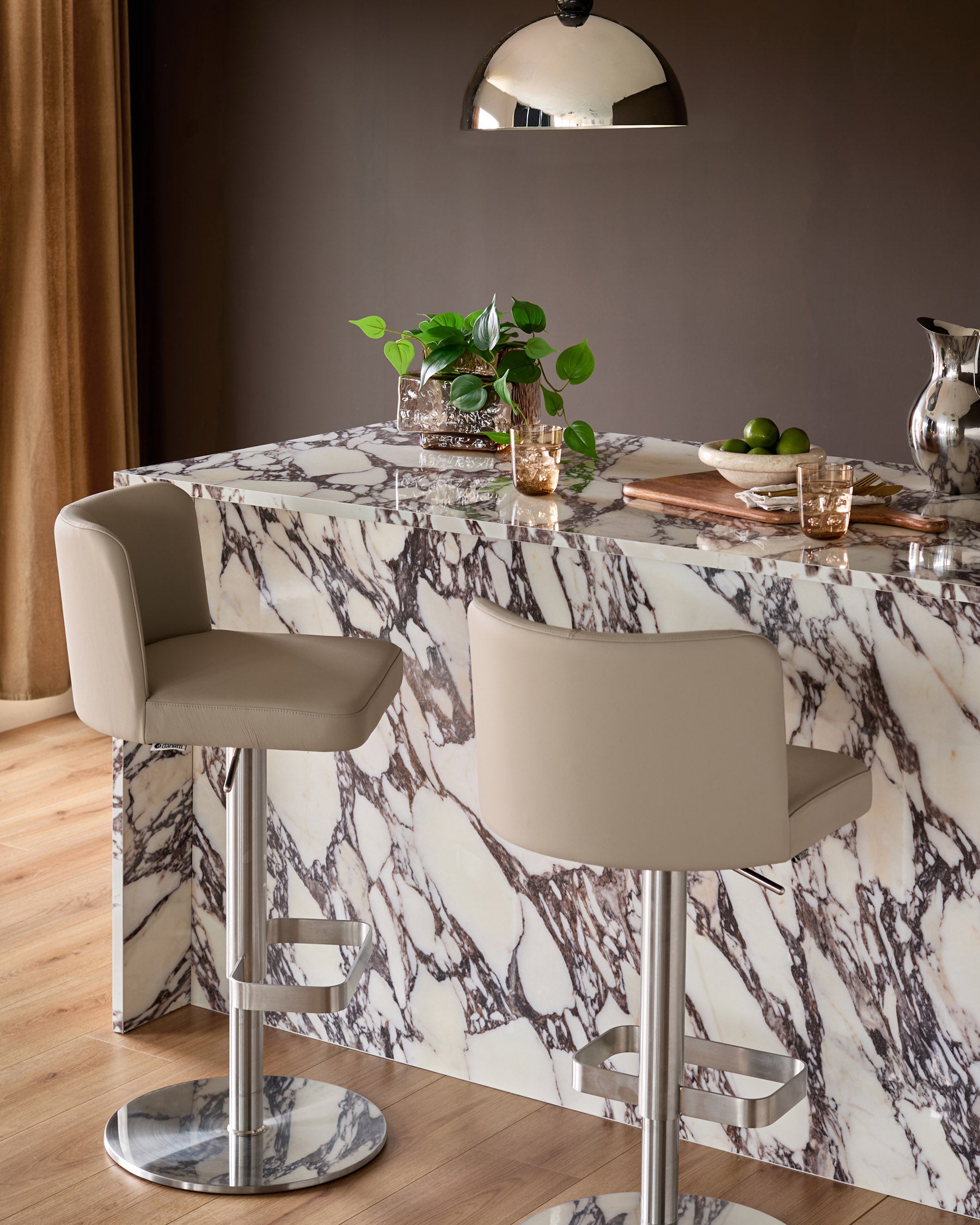 Light grey leather gas lift bar stool with curved backrest and polished chrome base, shown at marble dining counter.
