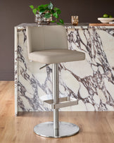 Arlo real leather gas lift bar stool in light grey, with brushed metal base, positioned at marble-effect counter.
