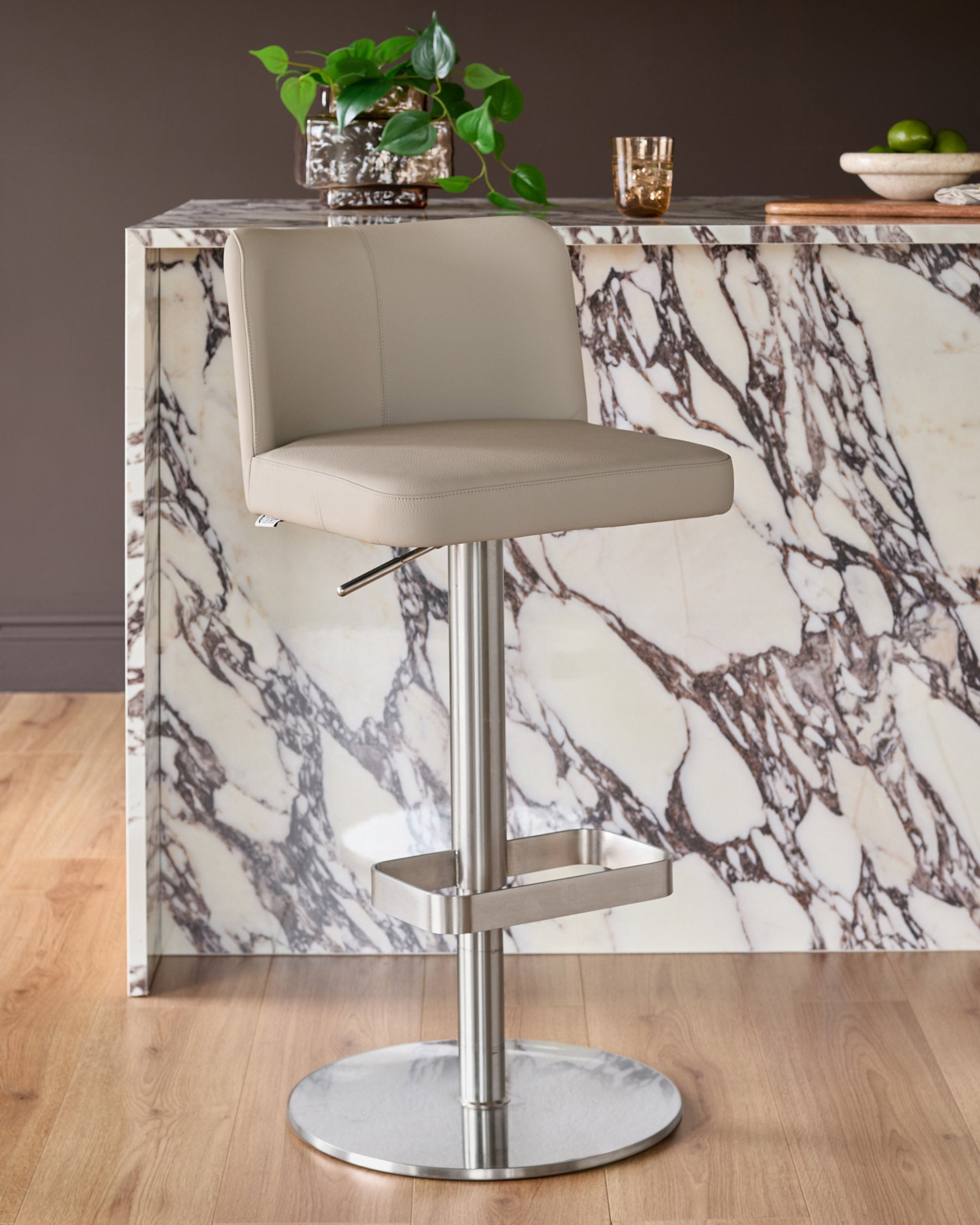 Arlo real leather gas lift bar stool in light grey, with brushed metal base, positioned at marble-effect counter.