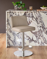 Arlo light grey leather gas lift bar stool with brushed metal base, positioned at marble countertop in modern kitchen setting.