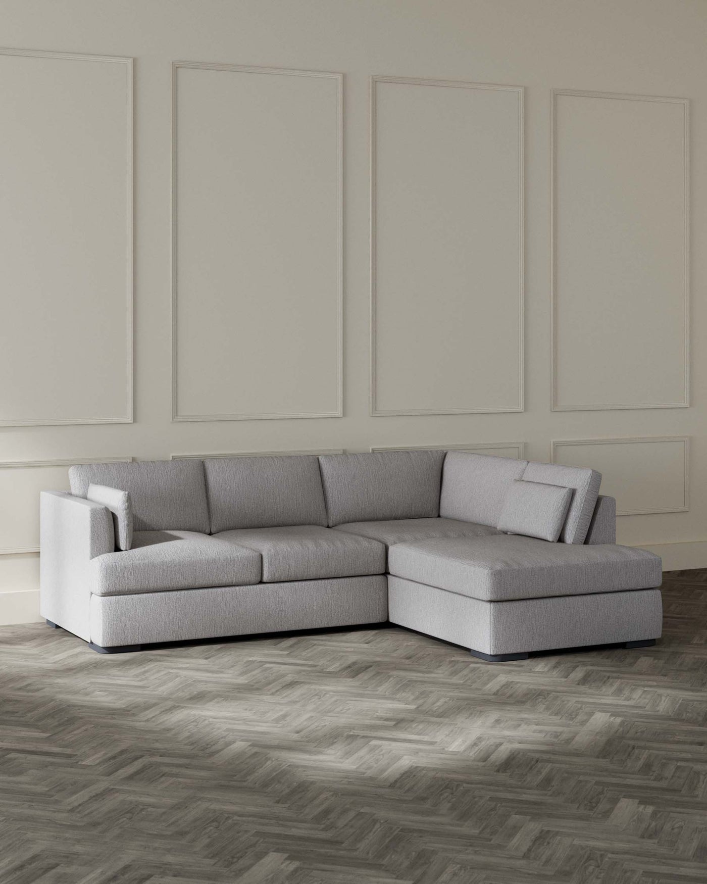 Modern light grey sectional sofa with clean lines and a minimalist aesthetic, featuring a chaise lounge extension, set against a neutral interior with decorative wall panels and herringbone wood flooring.