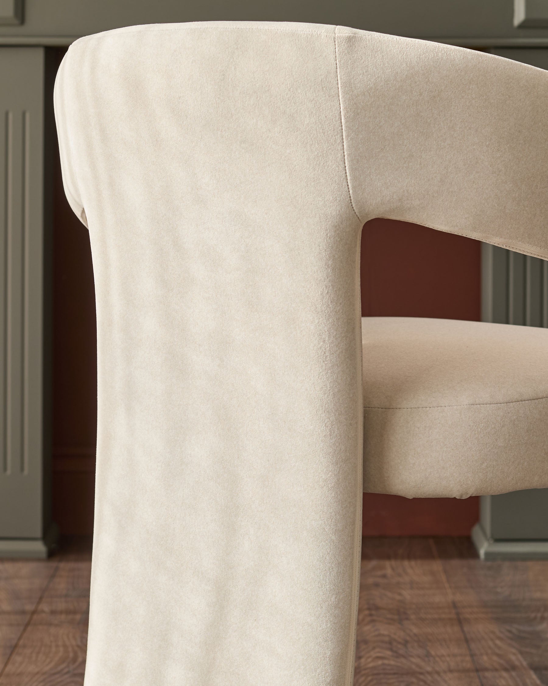 Cream fabric Asher dining chair, side view showing curved backrest and rolled arm detail on wooden legs.