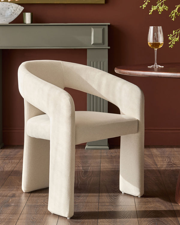 Cream fabric dining chair with curved, rounded arms and legs in a modern sculptural design, shown in an elegant room setting.