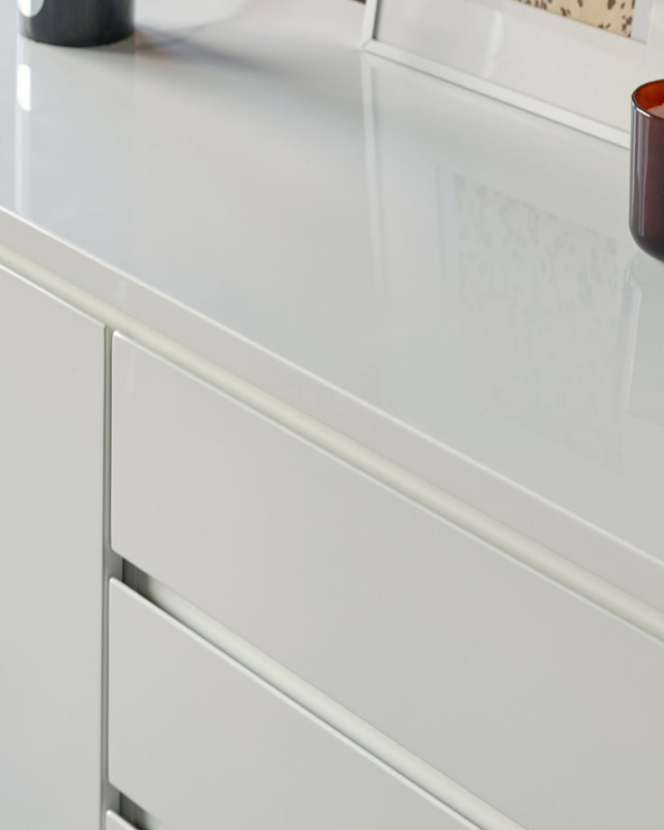 White gloss sideboard with integrated handle detail on drawer front, shown at an angle.