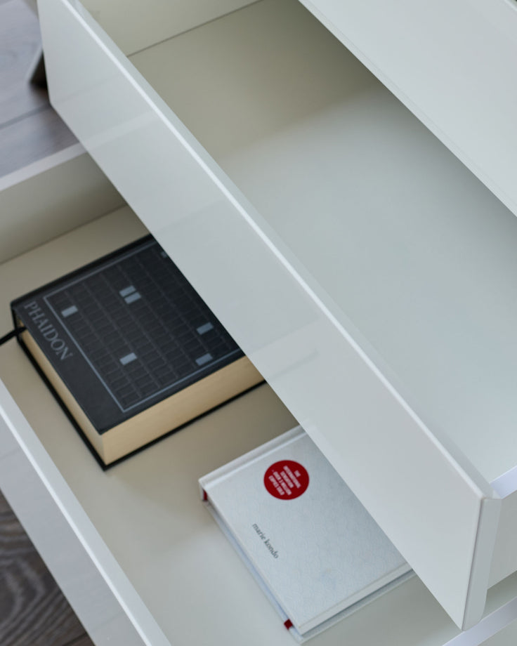 White gloss sideboard with open drawer displaying a dark control panel and white branded box inside.