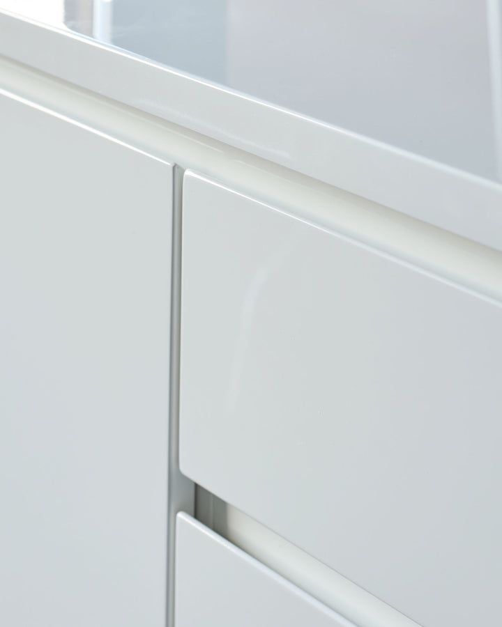 White gloss sideboard close-up showing minimalist recessed handle detail and sleek modern design.