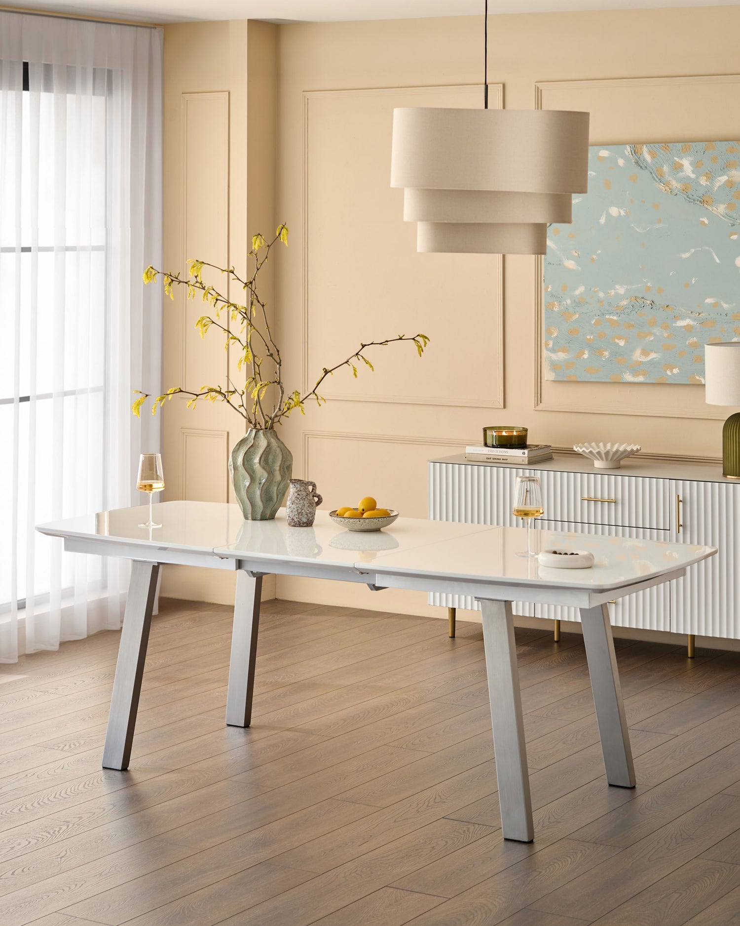 White extending dining table with light wood top and metal legs in modern dining room setting.
