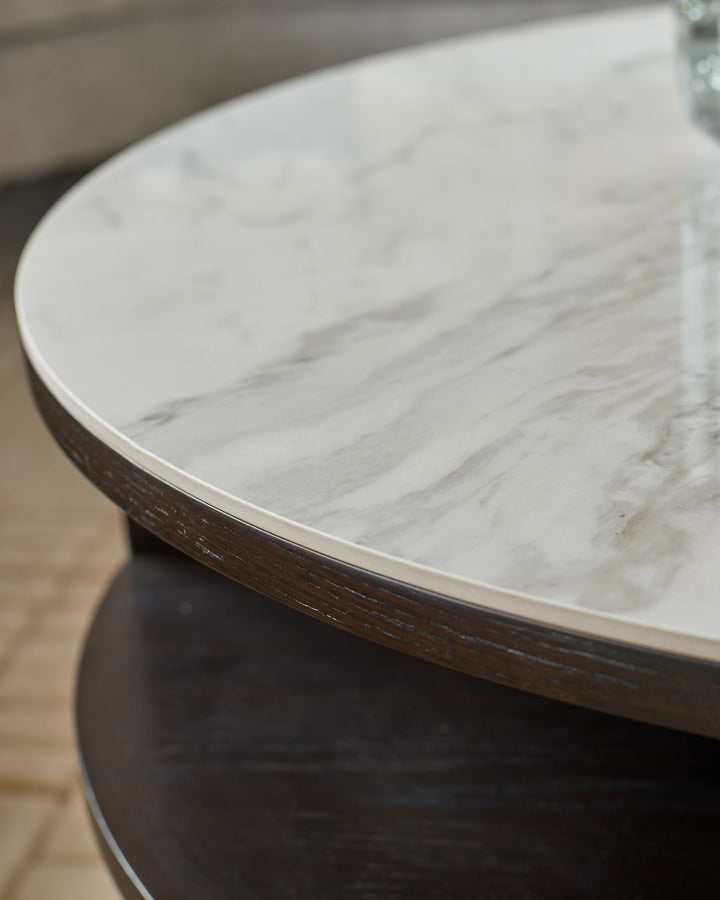 Aurora round coffee table with white marble top and dark oak wood base, angled side view.