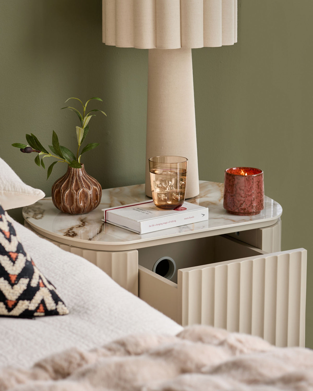 Austin bedside table in natural ceramic with rounded top, fluted drawer front, and open shelf storage below.