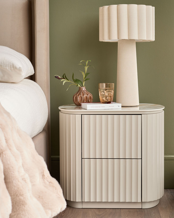 Austin bedside table in natural ceramic with vertical ribbed detailing, rounded corners, and two drawers, styled in a modern bedroom.