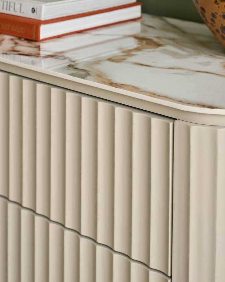 Austin chest of drawers in natural ceramic with vertical fluted detailing and marble-effect top surface.