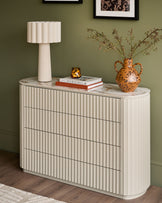 Austin chest of drawers in cream with fluted ribbed texture, marble top, and four drawers styled with lamp and decorative objects.