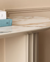 Austin console table in natural ceramic finish with cream-colored base and light wood top, styled with decorative books.