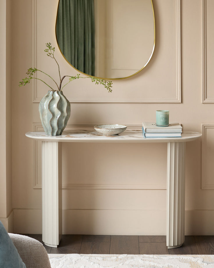 Austin ceramic console table in natural finish, oval shape with fluted column legs, styled with vase and decorative accessories.