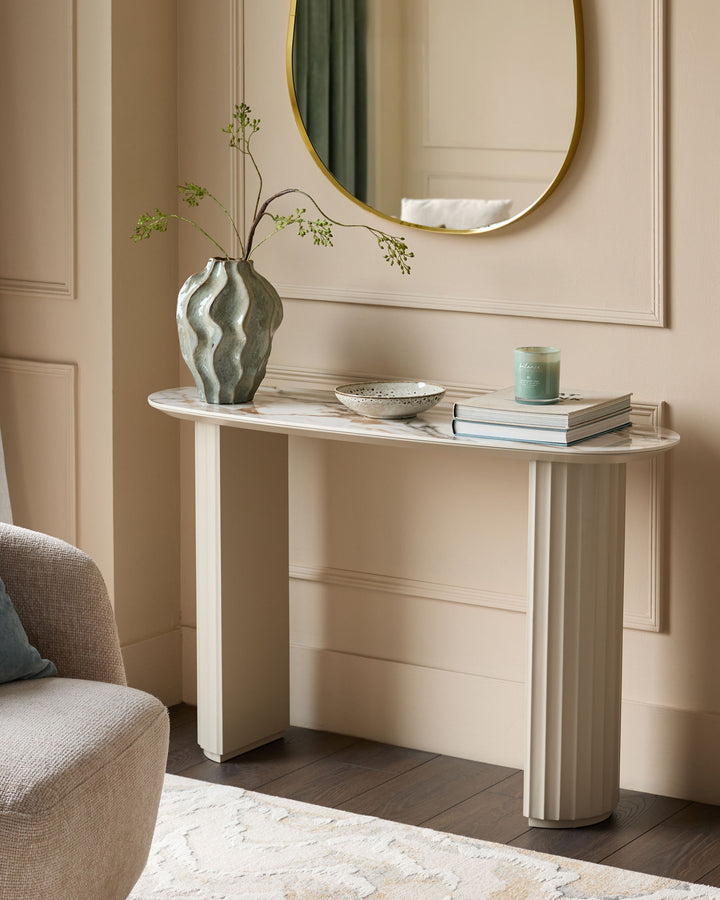 Austin console table in natural ceramic finish with curved white base and marble top, styled with vase and decor.