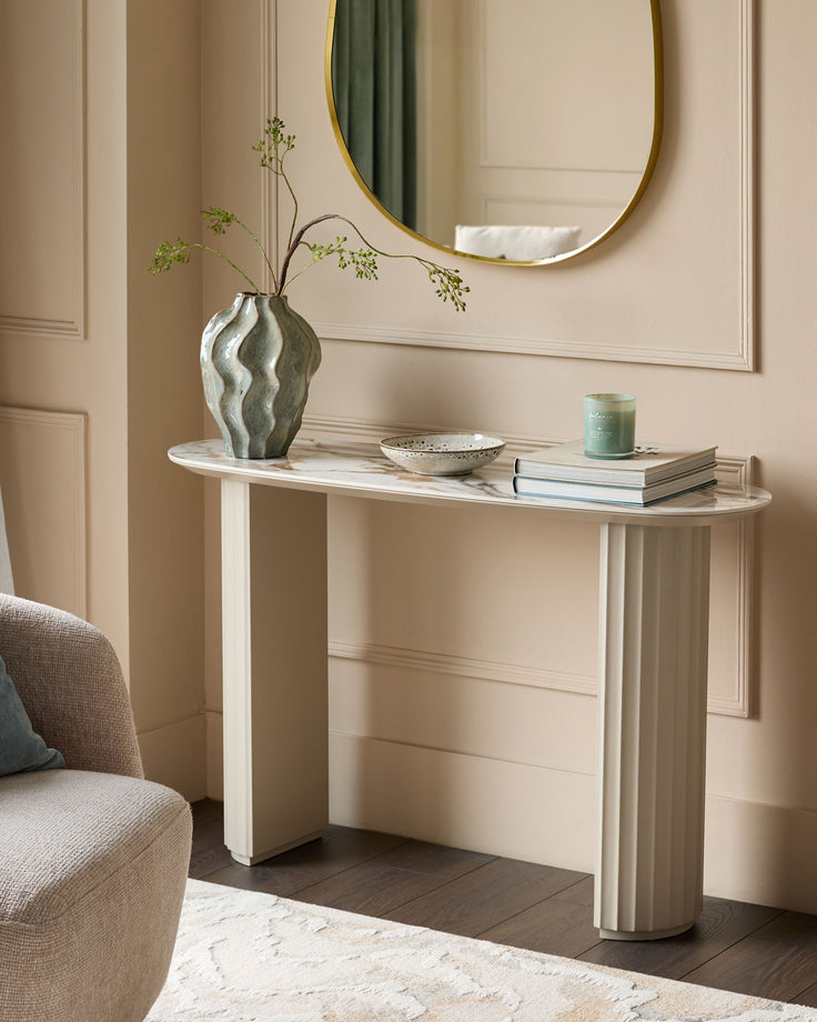 Austin console table in natural ceramic finish with curved white base and marble top, styled with vase and decor.