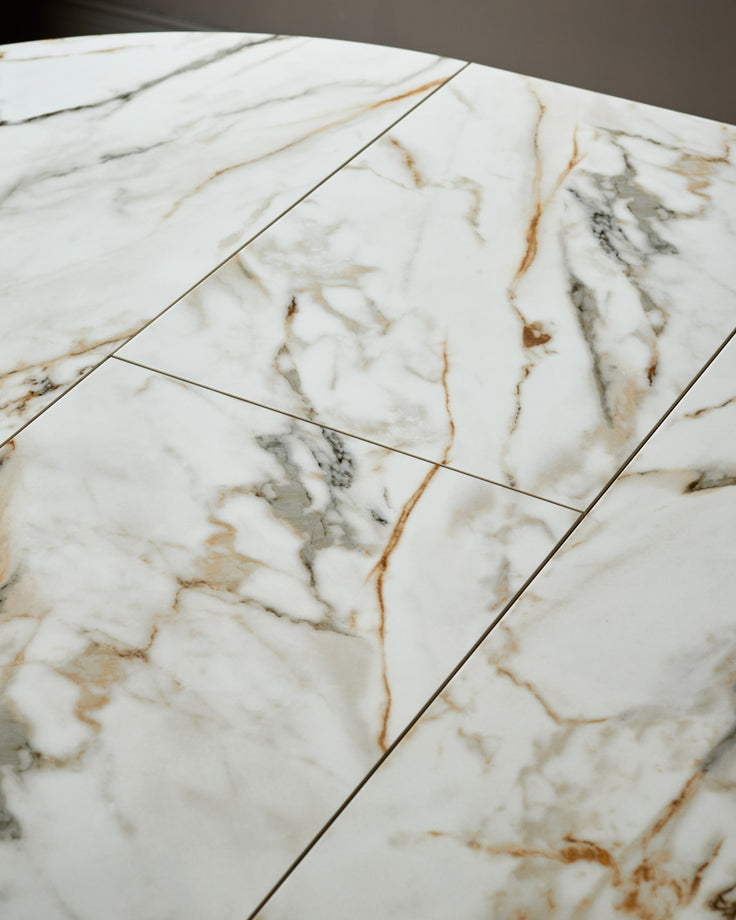Close-up of white marble tabletop with gold and grey veining, showing tile joints and polished finish.