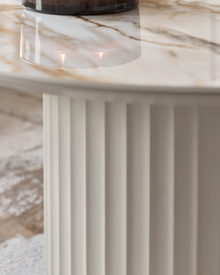 Marble-topped round table with fluted, cylindrical base. Contemporary design for modern interiors.