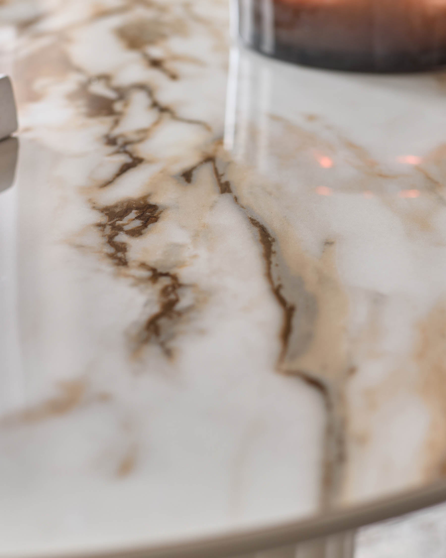 Close-up of a marble-effect table top, showcasing its natural, swirling patterns and smooth surface.