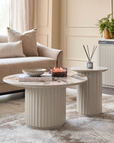 Elegant living room featuring round marble-topped coffee tables with fluted pedestals, paired with a neutral sofa.