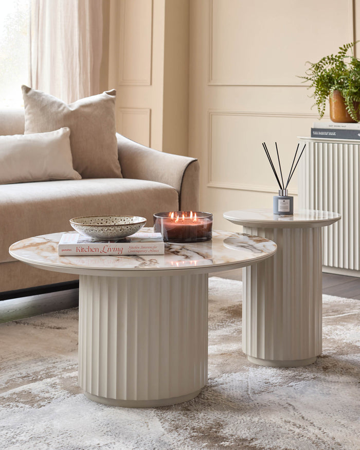 Elegant living room featuring round marble-topped coffee tables with fluted pedestals, paired with a neutral sofa.