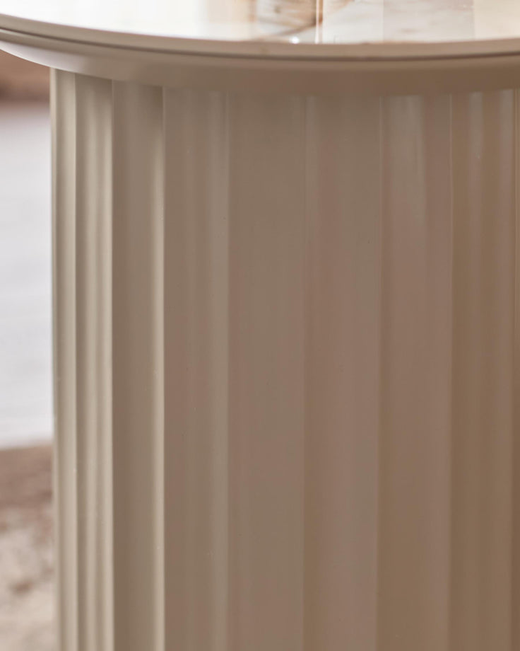 Close up of a beige pedestal table with a ribbed design. A sturdy and stylish piece of furniture.