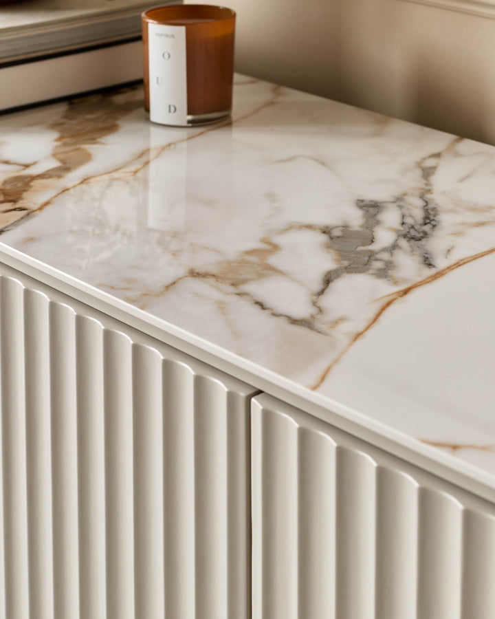 Close-up of a stylish sideboard with a marble top and textured cupboard doors, showcasing modern design.