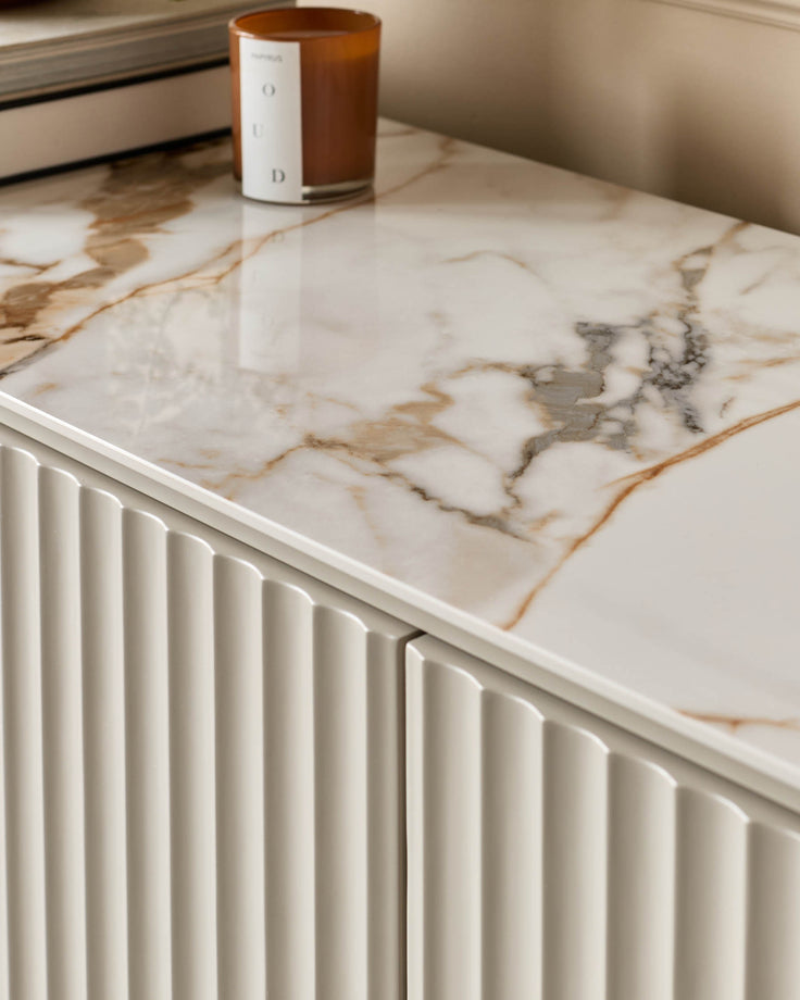 Close-up of a stylish sideboard with a marble top and textured cupboard doors, showcasing modern design.