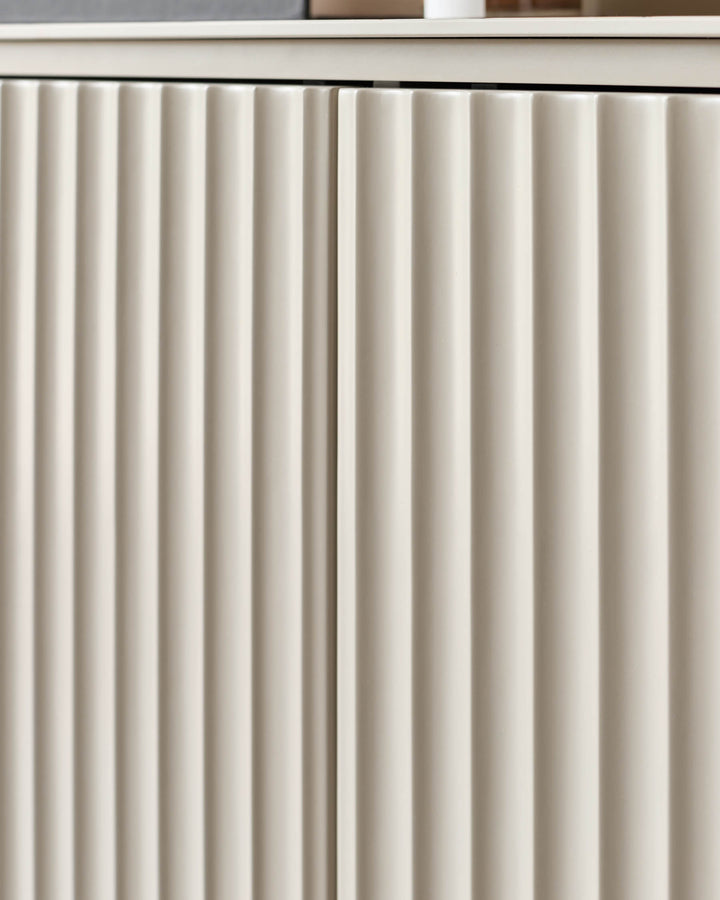 Close-up of a modern sideboard with white, vertically-ribbed door fronts and a smooth top.