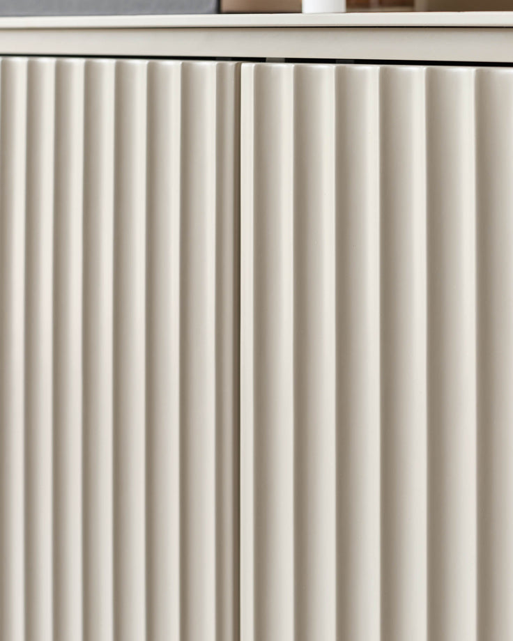 Close-up of a modern sideboard with white, vertically-ribbed door fronts and a smooth top.
