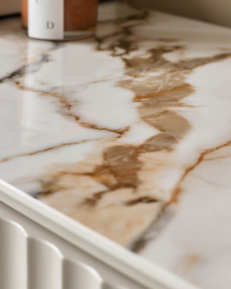 Close up of white marble-effect furniture surface, with decorative white trim detail.