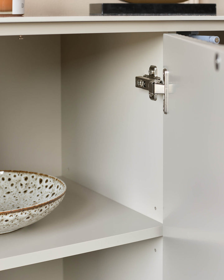 Close-up of a modern storage unit with an open cabinet door showing shelves and a decorative bowl.