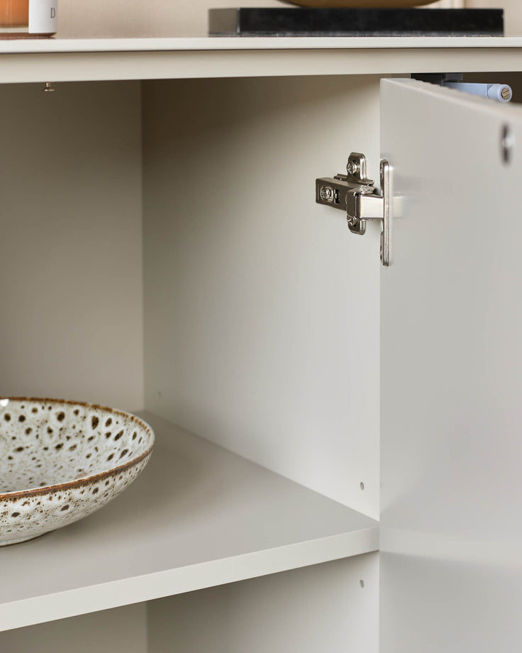 Close-up of a modern storage unit with an open cabinet door showing shelves and a decorative bowl.