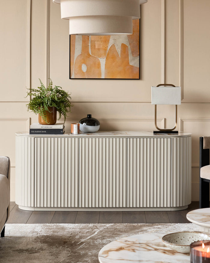 A stylish sideboard with ribbed doors, adorned with plant, lamp and vases. A neutral colour palette adds to the sophisticated design.