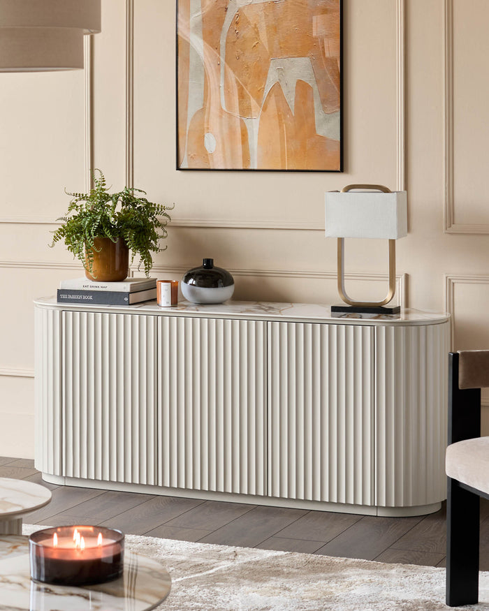 Stylish sideboard with reeded doors, adorned with decorative items and a lamp. A contemporary furniture piece.