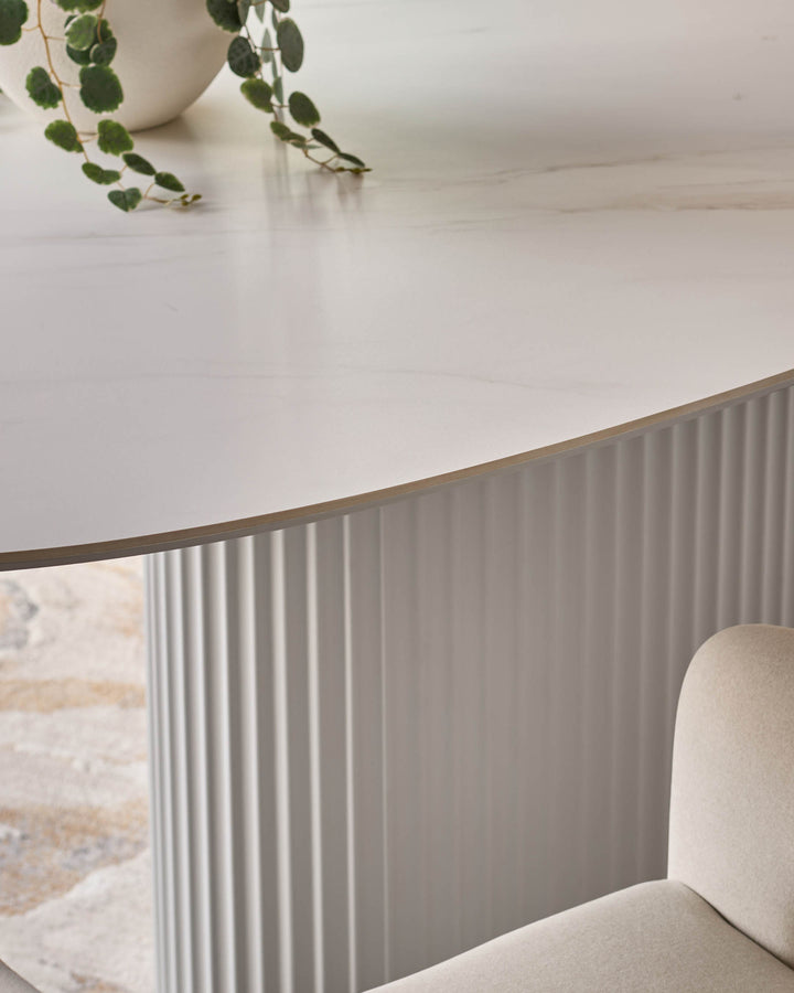 Austin ceramic fluted dining table in white with curved wooden edge detail and beige upholstered chair.