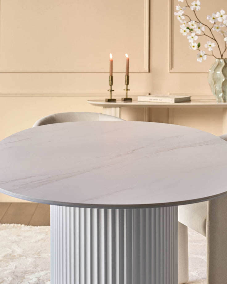 Austin ceramic fluted dining table in white with round top and ribbed pedestal base in a minimalist bedroom setting.