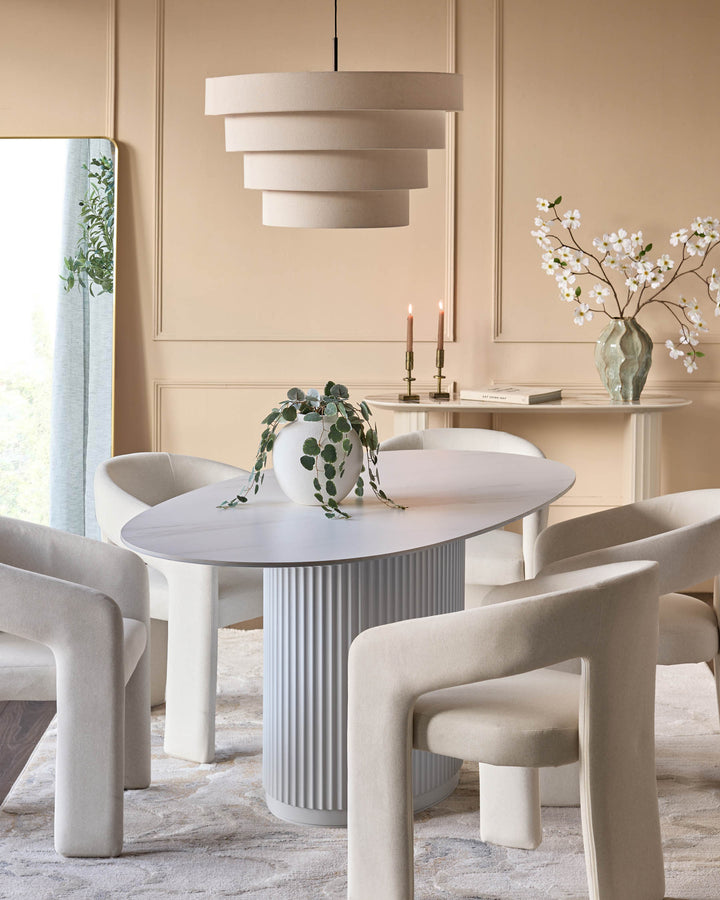 Austin ceramic fluted dining table in white, oval top with ribbed pedestal base, styled in bright dining room setting.