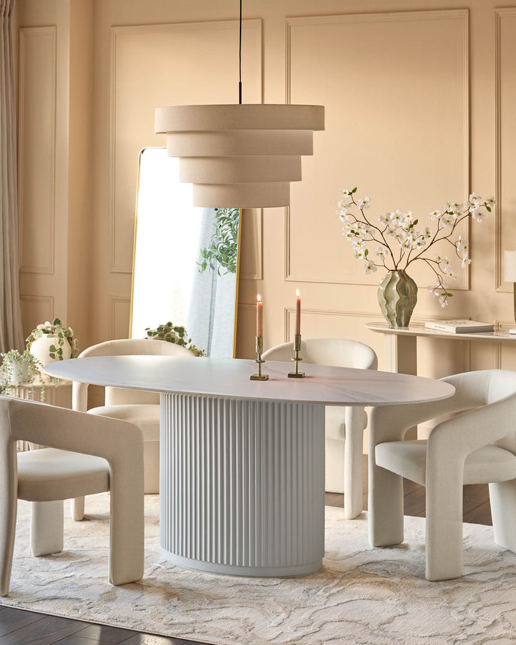 Austin ceramic fluted dining table in white with oval top and ribbed cylindrical base in a styled dining room setting.